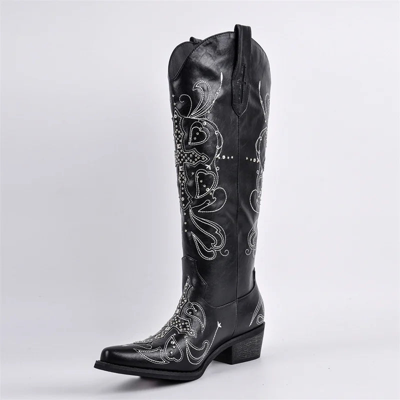 Black cowboy boot with intricate white embroidery on a light gray background