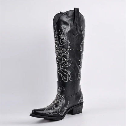 Black cowboy boot with intricate white embroidery on a light gray background