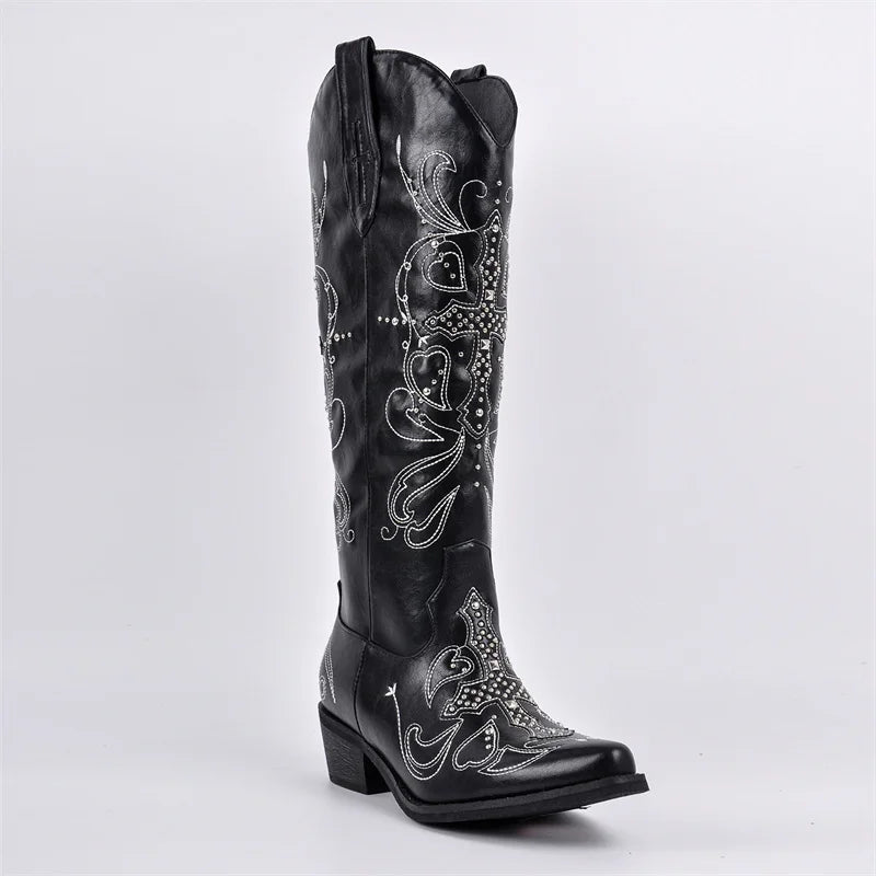 Black cowboy boot with intricate white embroidery on a light gray background