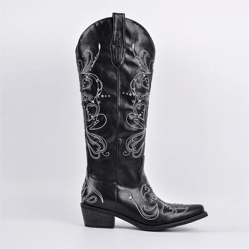 Black cowboy boot with intricate white embroidery on a light gray background