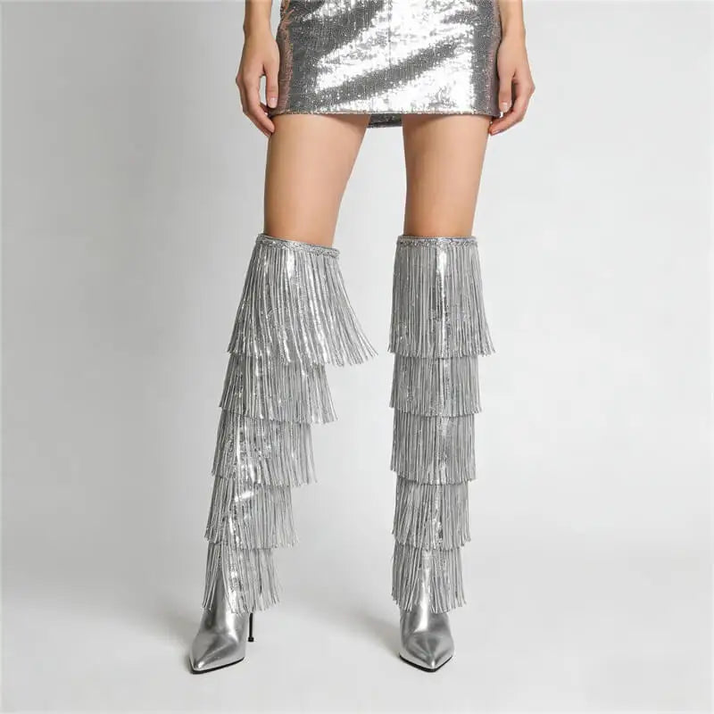 Silver fringe knee-high boots worn with a silver sequin skirt on a light gray background