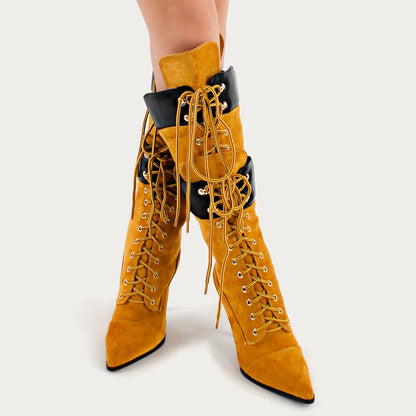 Mustard yellow knee-high boots with black accents on a white background