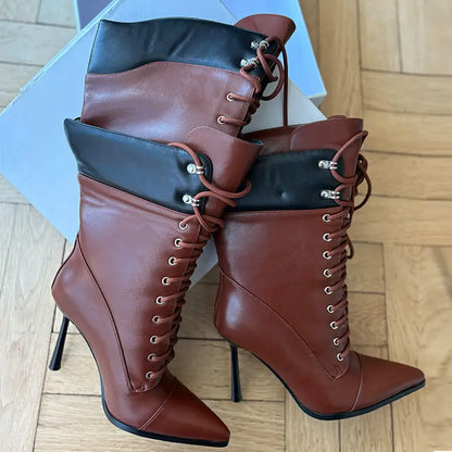 Brown high-heeled boots with black accents on a wooden floor.