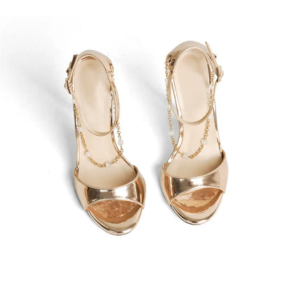 Pair of gold high-heeled shoes with chain details on a white background
