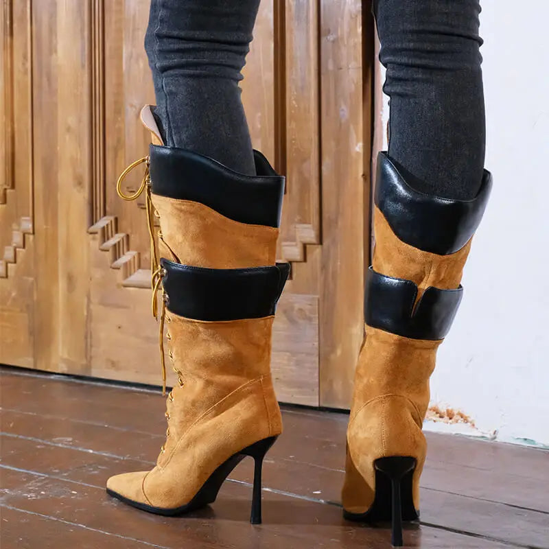 Tan knee-high boots with black accents worn by a person against a wooden panel background.